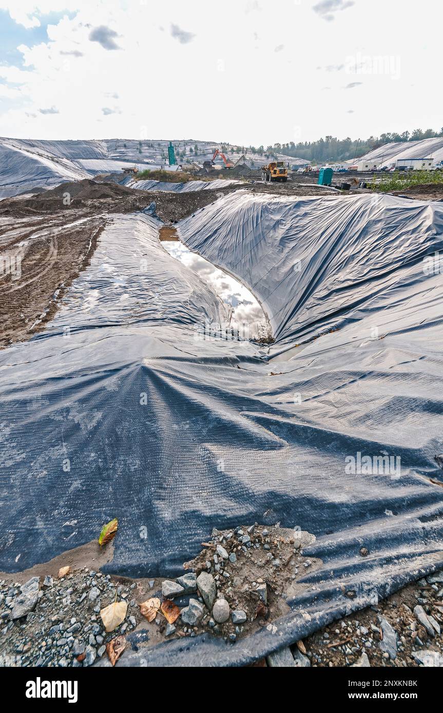 Vast areas of excavation and plastic geomembrane coverings at an active landfill. Stock Photo
