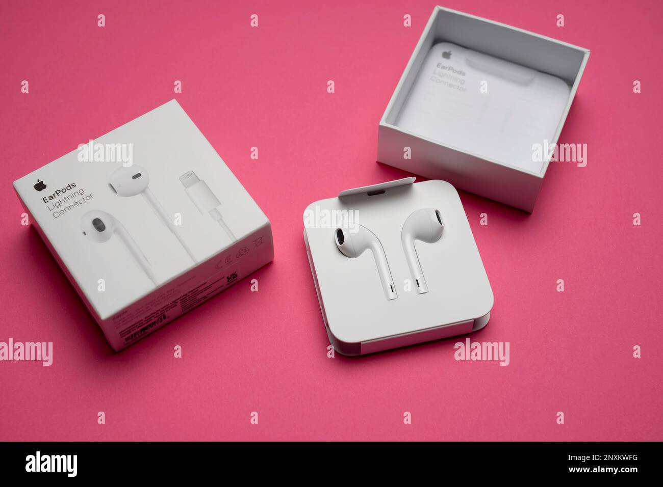 New Apple Earpods, Airpods white earphones for listening to music and podcasts in an open box. Isolated pink background. Budapest, Hungary - February Stock Photo