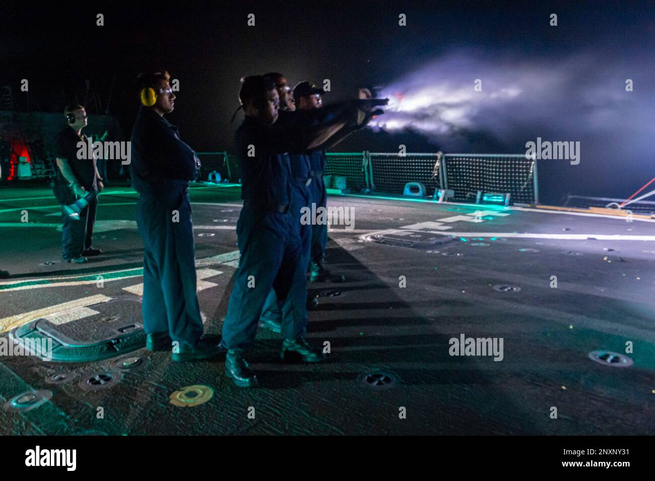 230123-N-NH267-2122 PACIFIC OCEAN (Jan. 23, 2023) U.S. Navy Intelligence Specialist 1st Class Roger Bajet, from San Diego, fires an M9 pistol during a low-light small arms fire on the flight deck of the Arleigh Burke-class guided-missile destroyer USS Paul Hamilton (DDG 60). Paul Hamilton, part of the Nimitz Carrier Strike Group, is underway conducting routine operations. Stock Photo