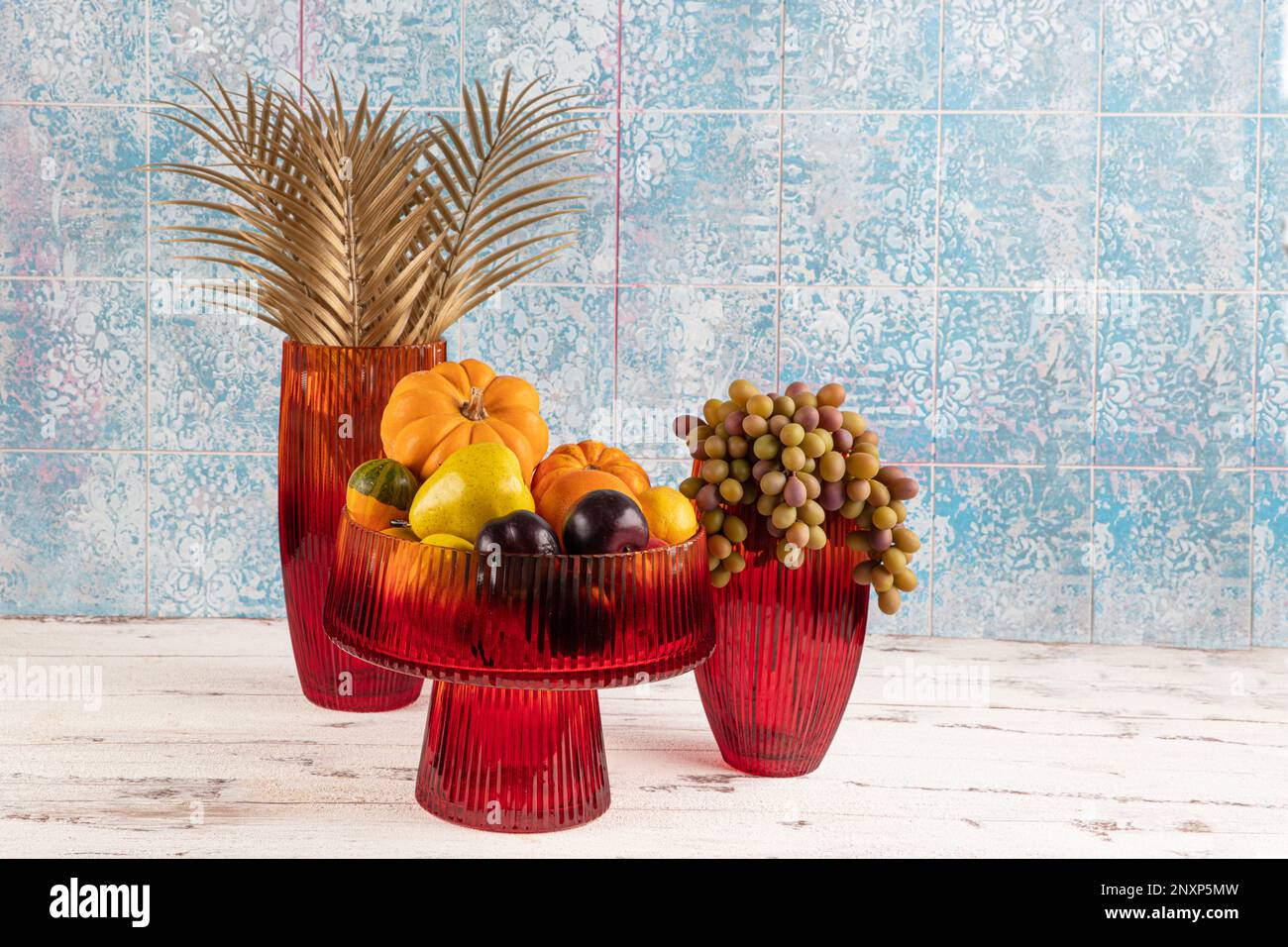 Ornamental pumpkin, fruit and grapes in a vase. Colored Glass vase