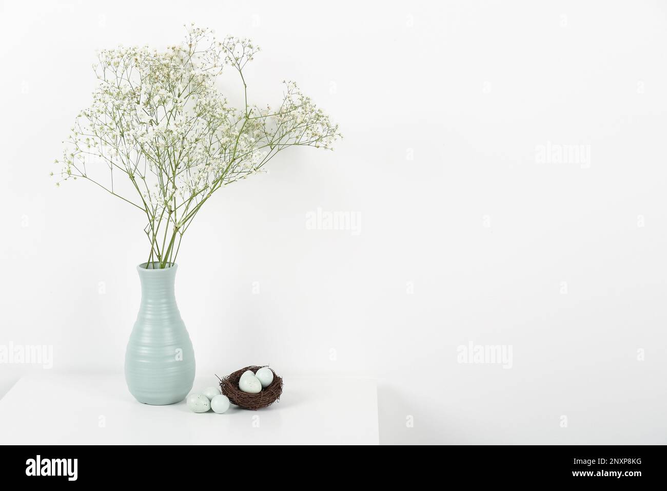 Vase with gypsophila flowers and Easter eggs on white background Stock ...