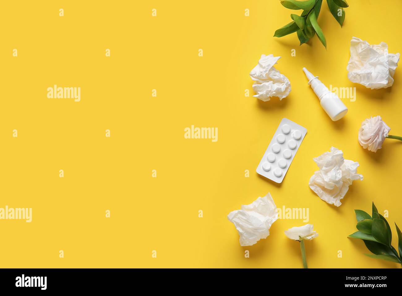 Nasal drops with pills, flowers and tissues on yellow background