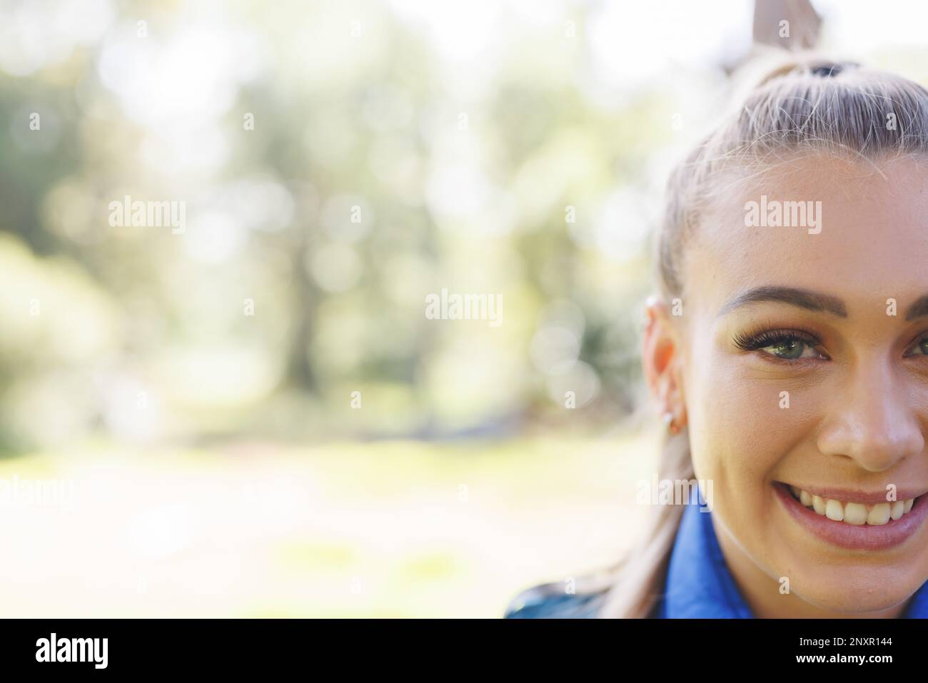 Half face portrait of smiling blonde caucasian woman trekking in sunny forest, copy space Stock Photo