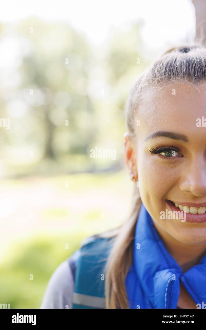 Vertical half face portrait of smiling blonde caucasian woman trekking in sunny forest, copy space Stock Photo