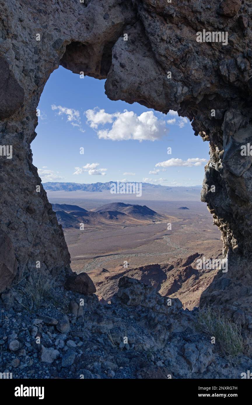 rock arch window looking out over the Mojave Desert in the Turtle Mountains of eastern California Stock Photo