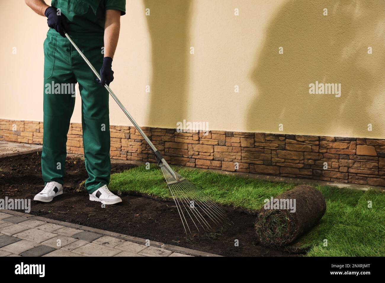 Worker leveling soil before laying grass sod at backyard, closeup Stock