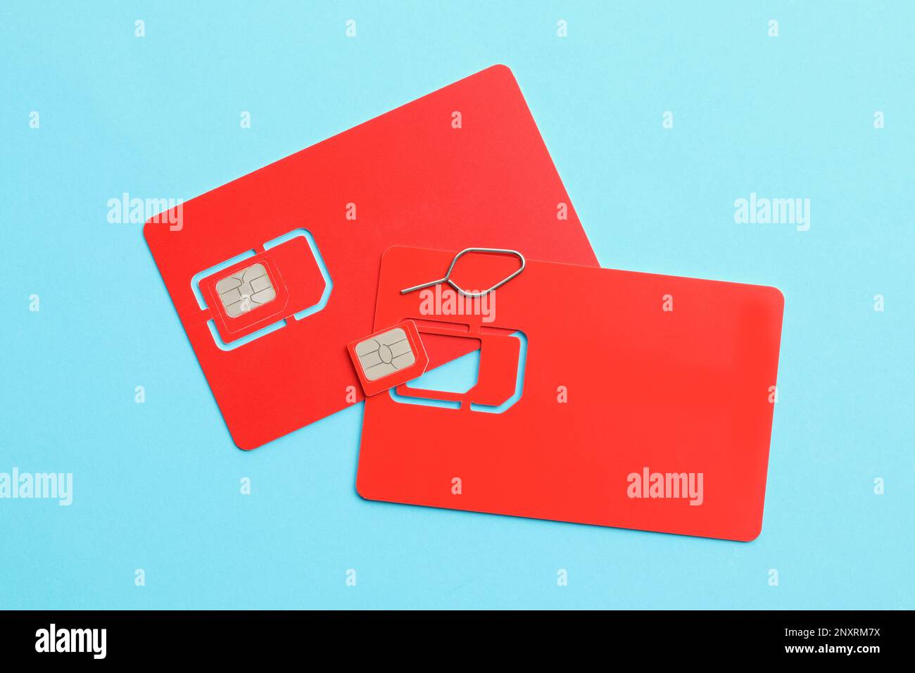Red SIM cards on light blue background, flat lay Stock Photo
