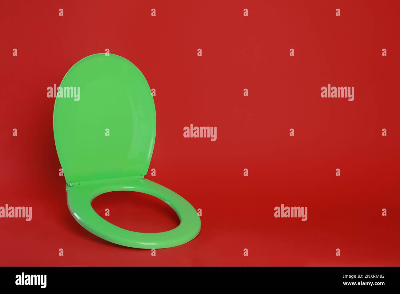 New green plastic toilet seat on red background, space for text Stock Photo