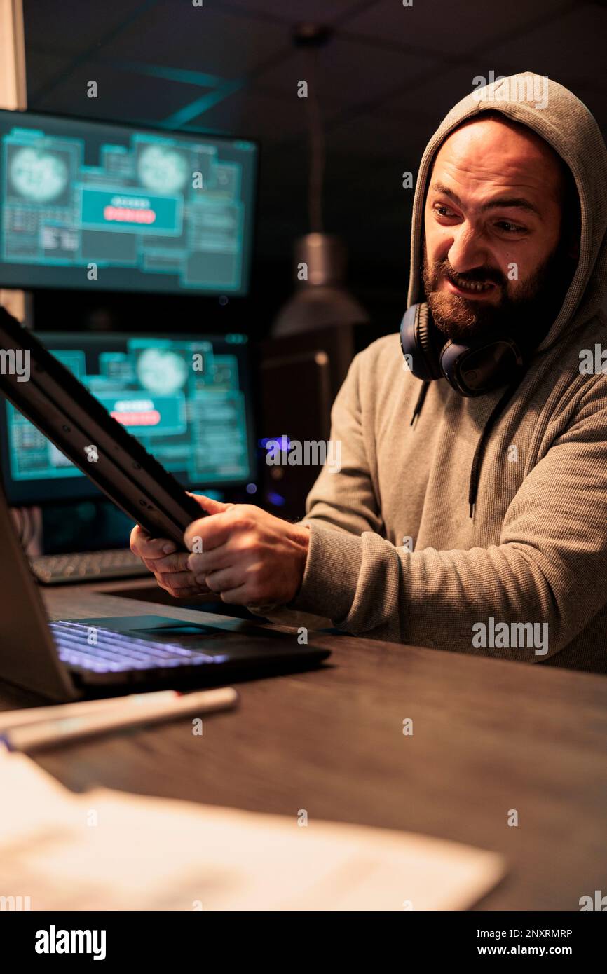 Aggressive violent hacker throwing keyboard in office, feeling angry