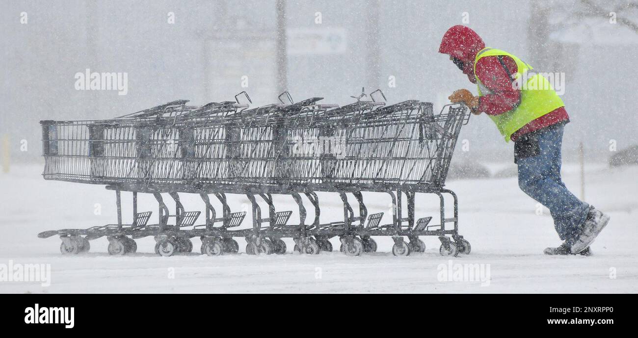 A Stop and Shop supermarket employee struggles to push a train of