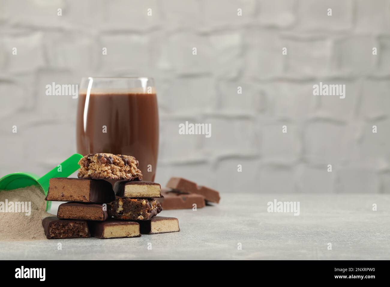 Different energy bars, protein cocktail and powder on grey table. Space