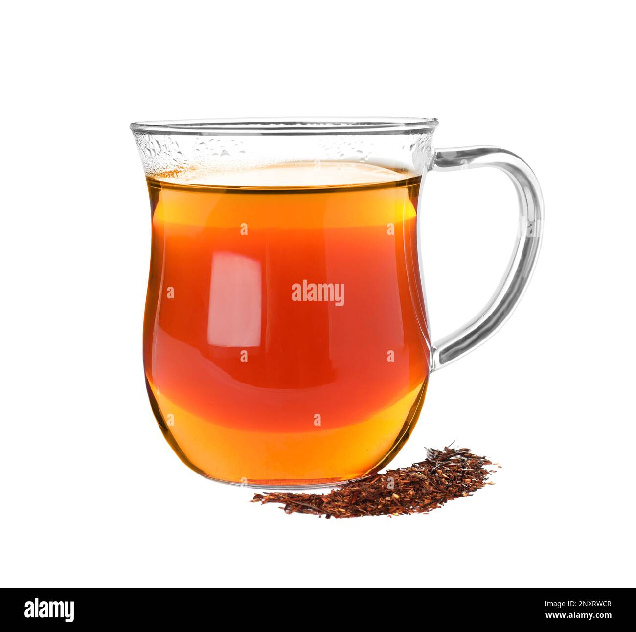 Aromatic rooibos tea in glass cup and scattered dry leaves on white