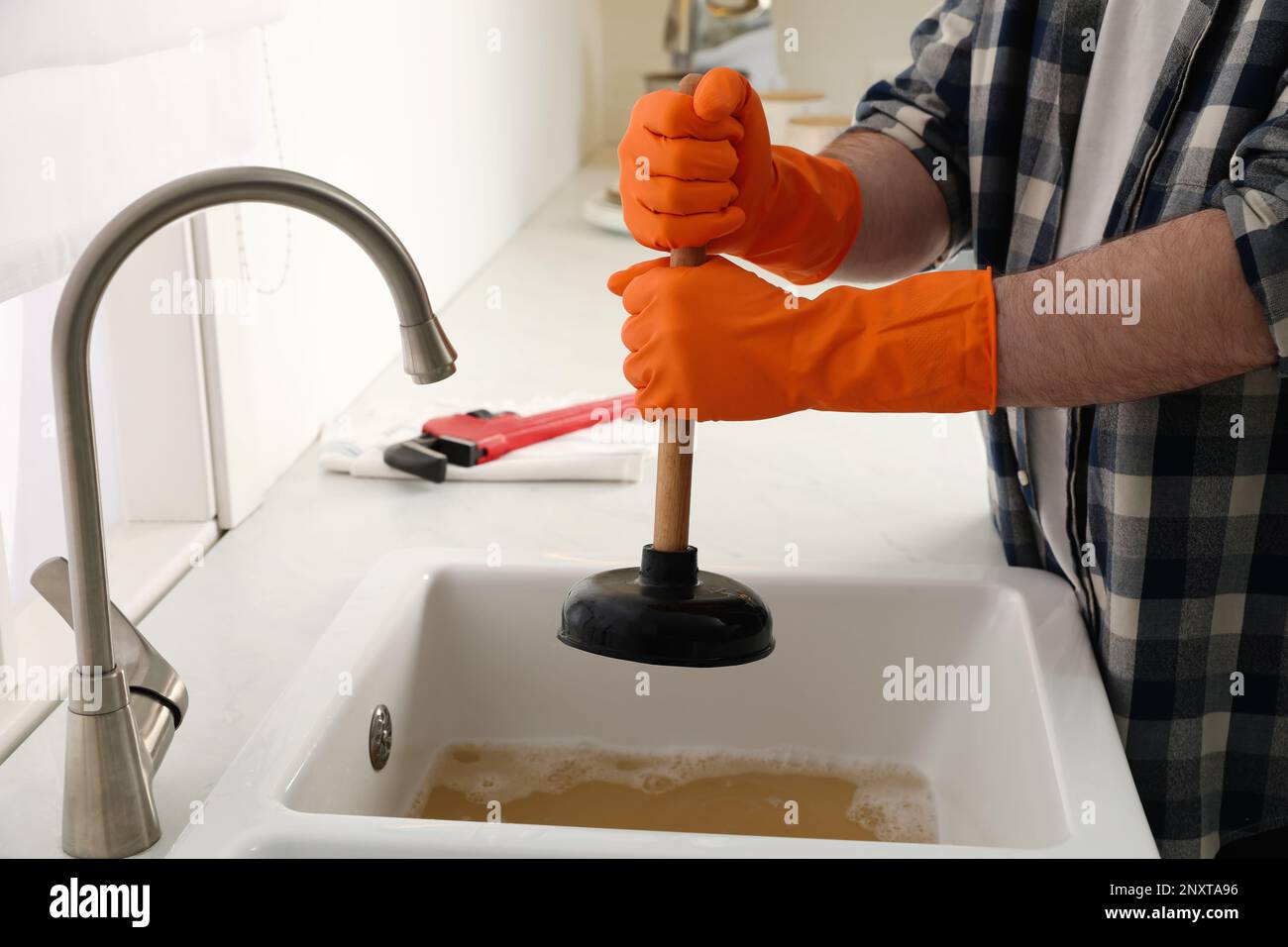 https://c8.alamy.com/comp/2NXTA96/man-using-plunger-to-unclog-sink-drain-in-kitchen-closeup-2NXTA96.jpg