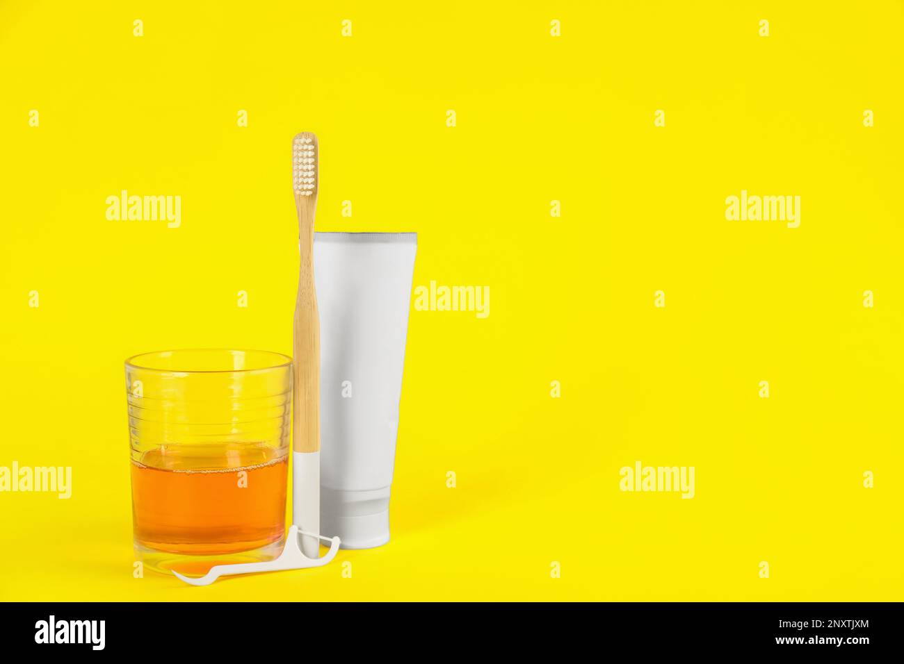 Mouthwash, toothbrush, paste and dental floss pick on yellow background ...