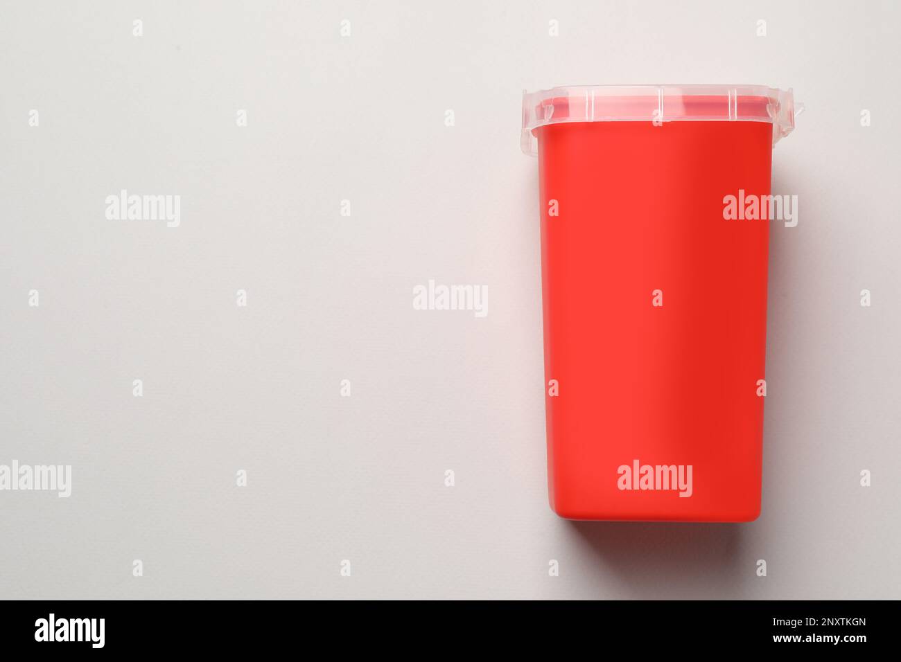 Sharps container for used syringe on light background, top view. Space
