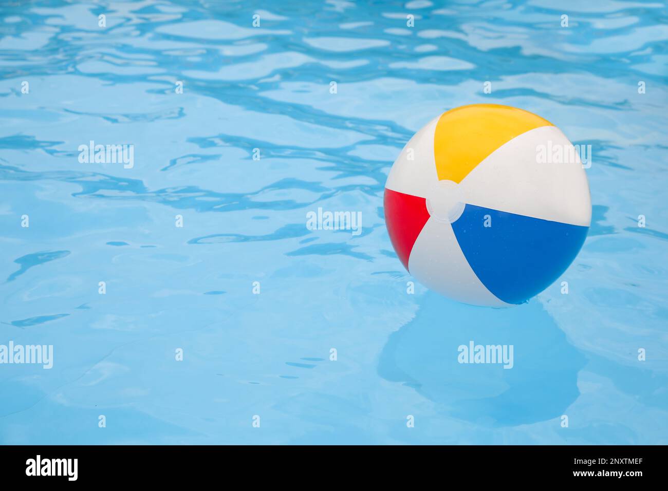 Inflatable colorful beach ball floating on water in swimming pool
