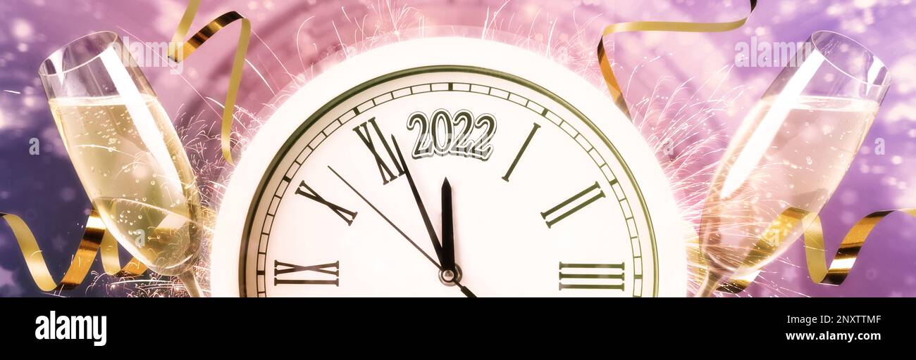 Glasses of sparkling wine, clock, shiny streamers and firework on color