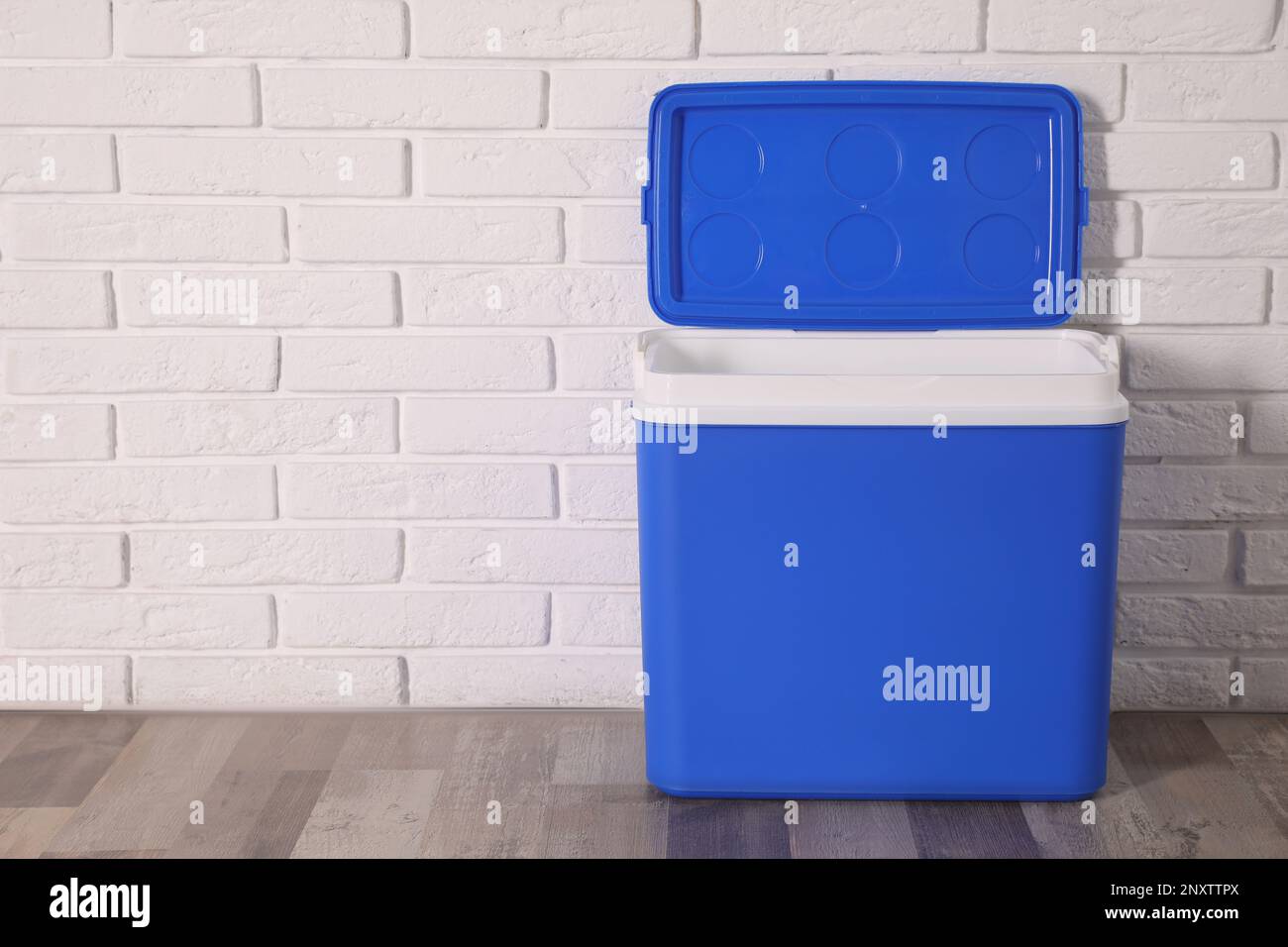 Open blue plastic cool box near white brick wall. Space for text Stock Photo Alamy