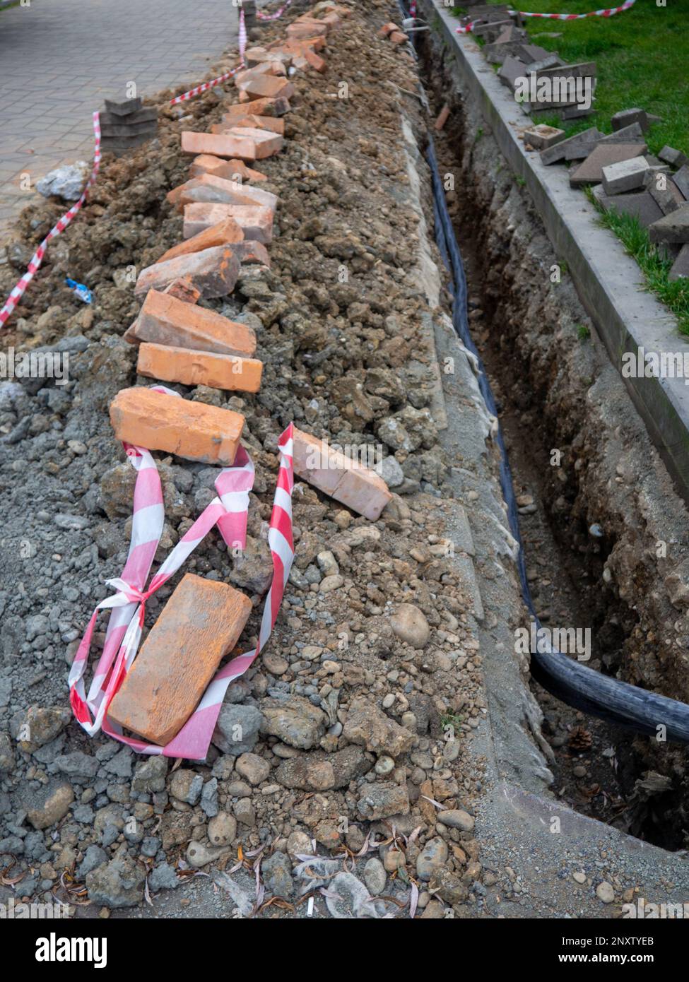 Broken sidewalk. Conducting the cable underground. Cable laying work