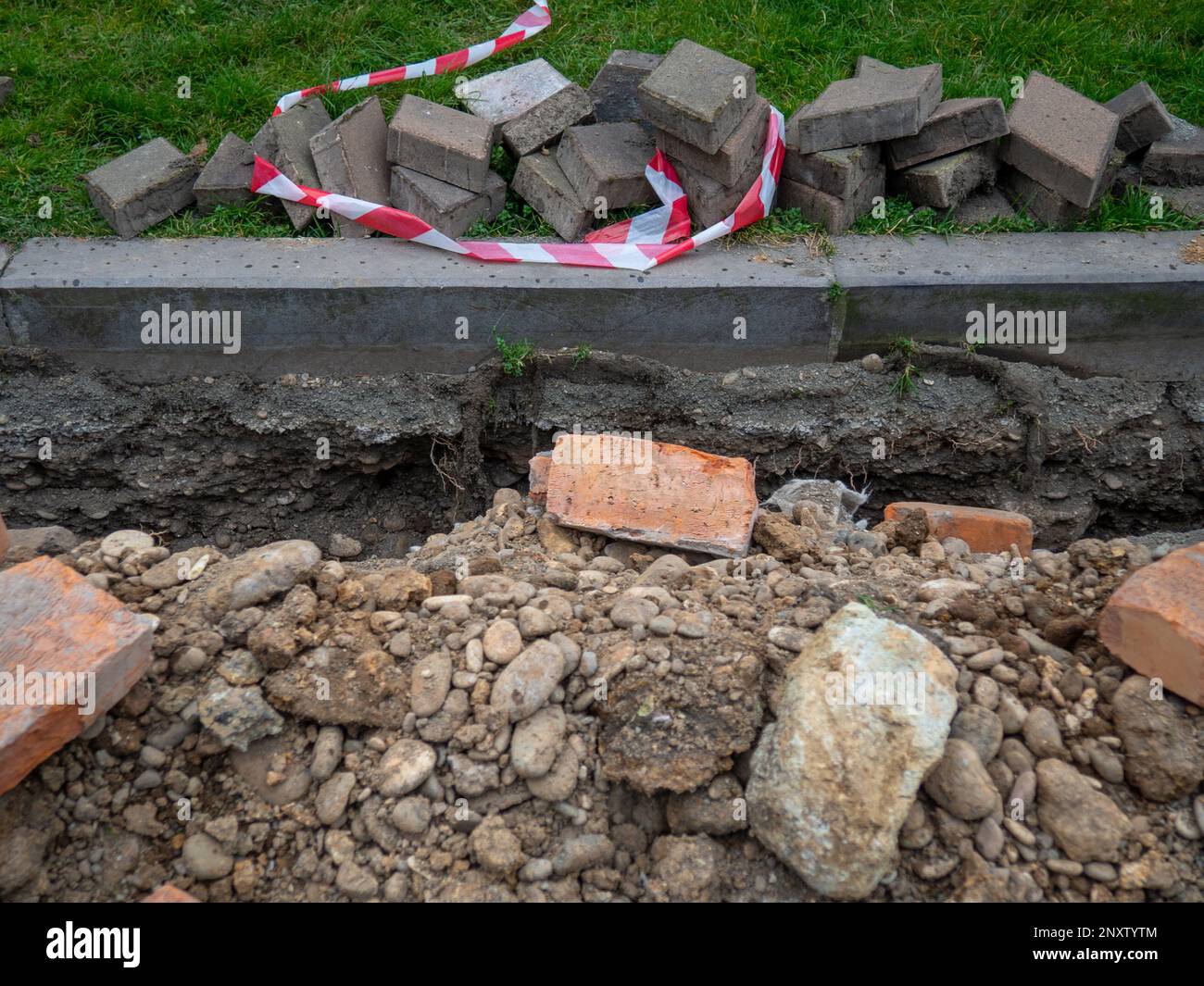 Broken sidewalk. Conducting the cable underground. Cable laying work. Communications in the city. Digged paving bricks. Pedestrian area renovation Stock Photo