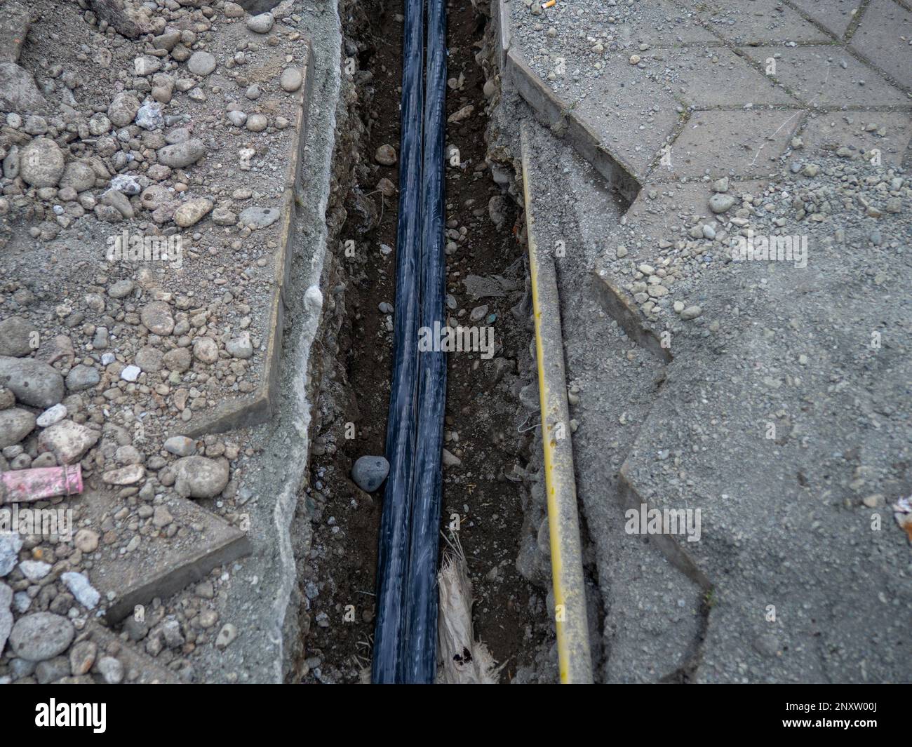 Broken sidewalk. Conducting the cable underground. Cable laying work