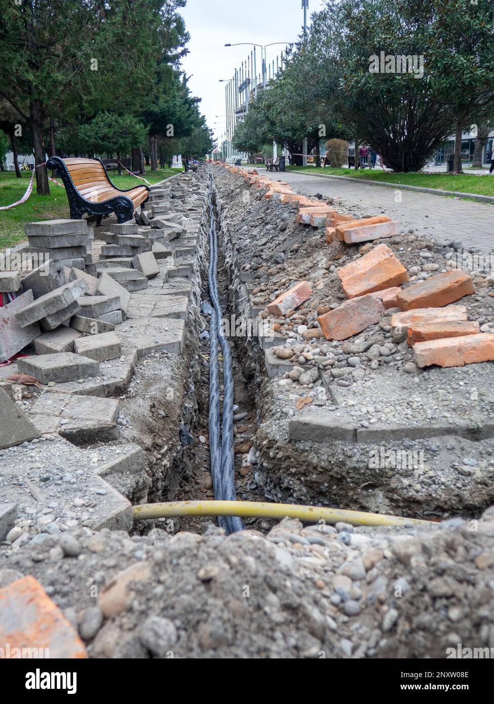 Broken sidewalk. Conducting the cable underground. Cable laying work
