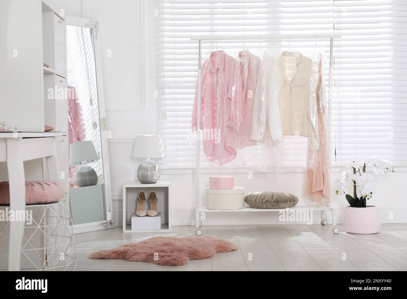 Rack with clothes in plastic bags indoors Stock Photo Alamy