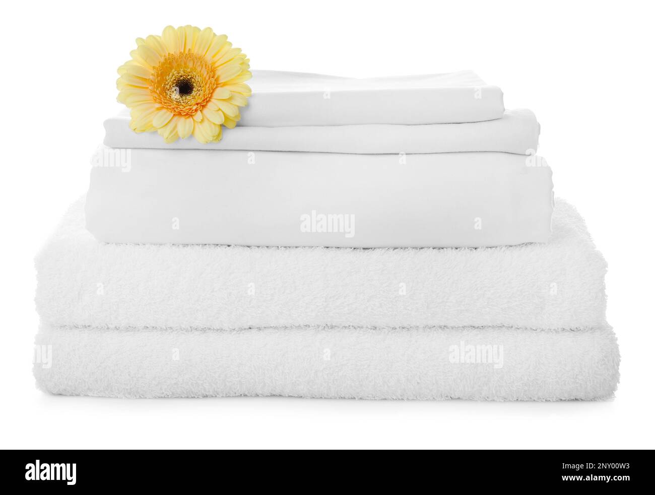 Stack of towels and bed sheets with gerbera on white background Stock
