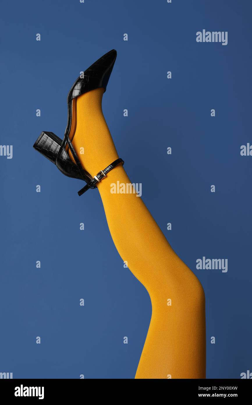 Woman wearing bright tights and high heel shoe on blue background, closeup Stock Photo