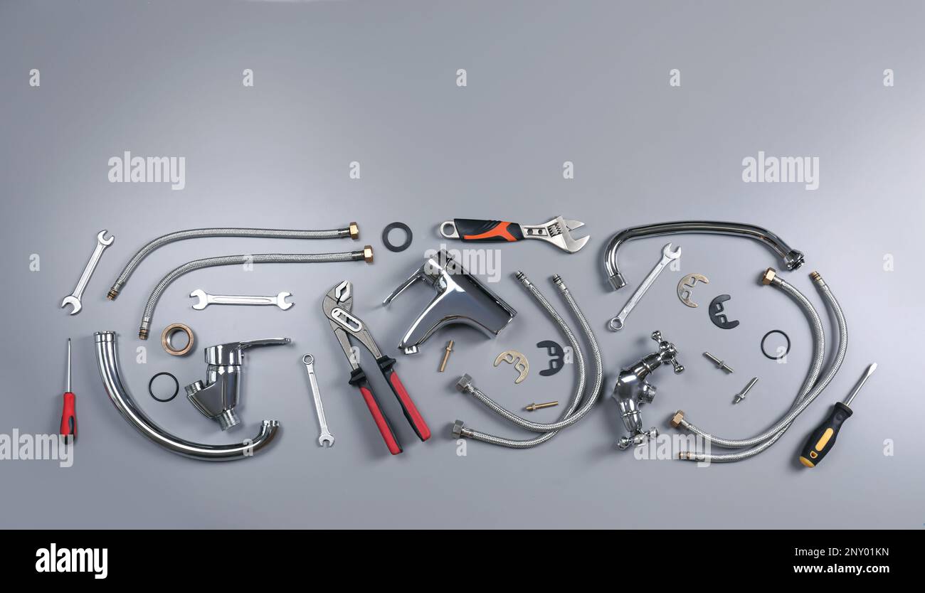 Parts of water tap and plumber tools on grey background, flat lay Stock