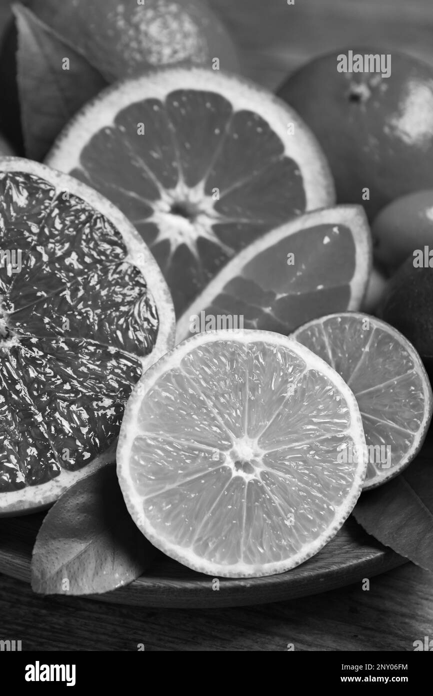 Fresh juicy citrus fruits on plate, closeup. Black and white tone Stock Photo