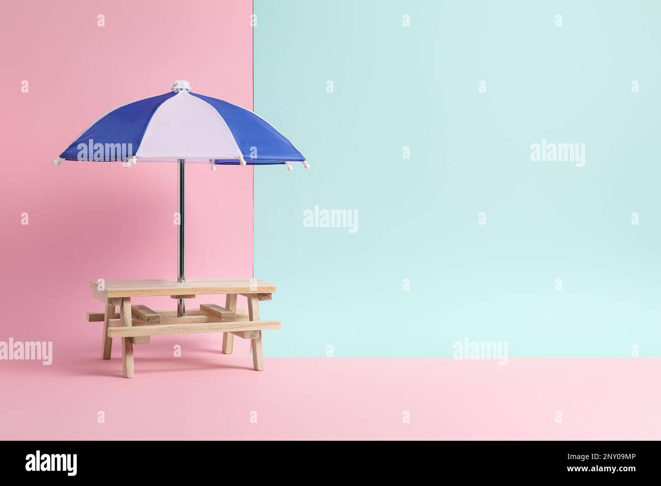 Small wooden holder with toy umbrella on color background, space for text Stock Photo