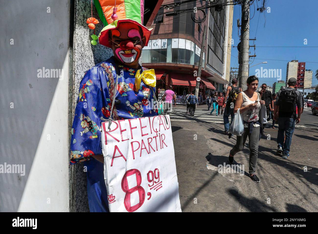 SP - São Paulo - 11/16/2017 - SPECIAL INFORMALITY - A man dressed as a  clown shows a poster with food values in the neighborhood of Bras, a region  known in the