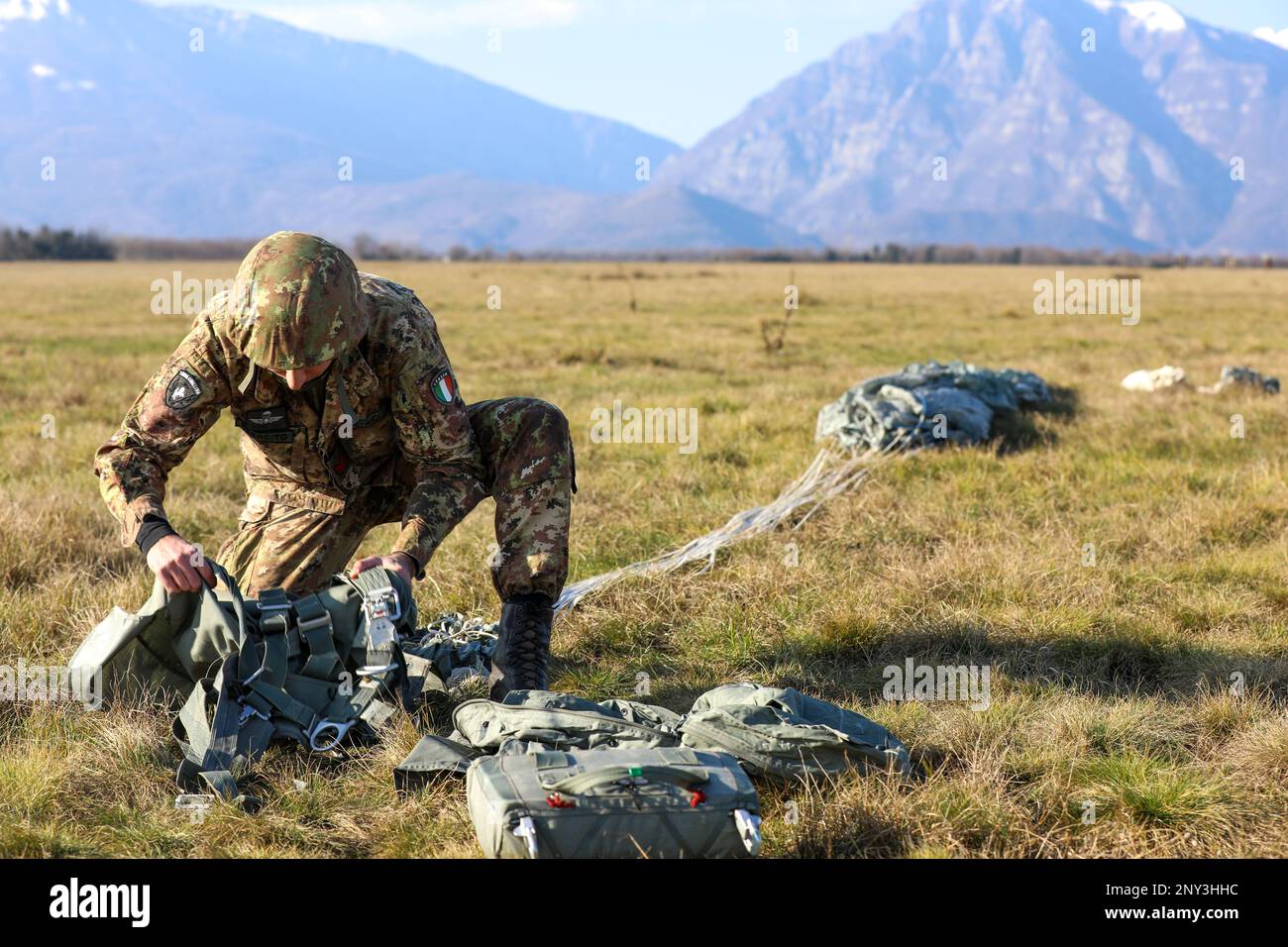 An Italian Army paratrooper with the Brigata Paracadutisti 'Folgore' repacks his chute after landing near Aviano, Italy on Jan. 26, 2023. The 173rd Airborne Brigade is the U.S. Army's Contingency Response Force in Europe, providing rapid forces to the United States European, Africa and Central Commands areas of responsibilities. Forward-based in Italy and Germany, the Brigade routinely trains alongside NATO allies and partners to build interoperability and strengthen the Alliance. Stock Photo