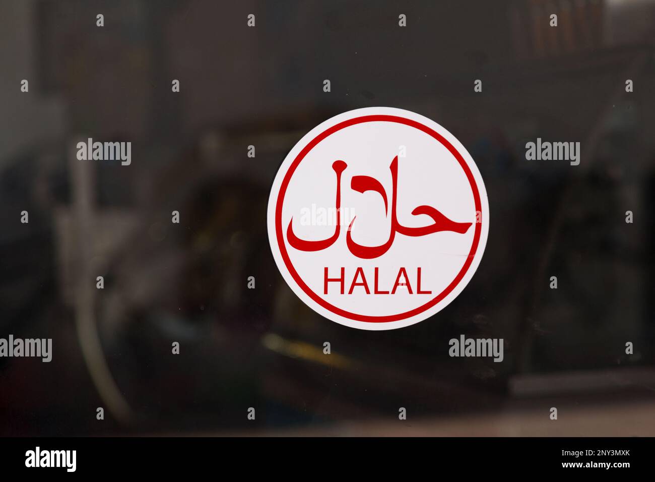 Circular sign in a window with written in arabic “حلال”, meaning “Halal”. Stock Photo