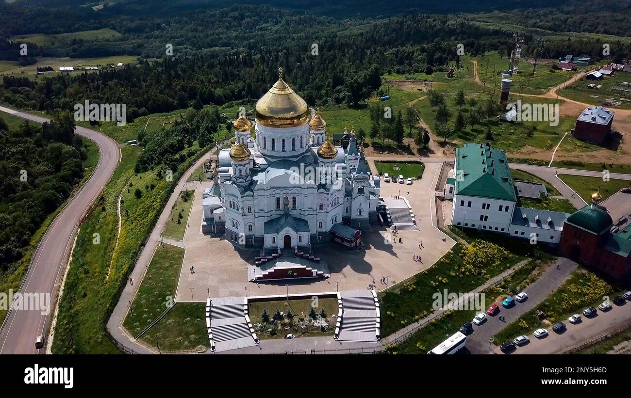 View from a height of a summer landscape with a forest and mountains. Clip. A green forest with spruces and a beautiful peasant temple in the middle s Stock Photo