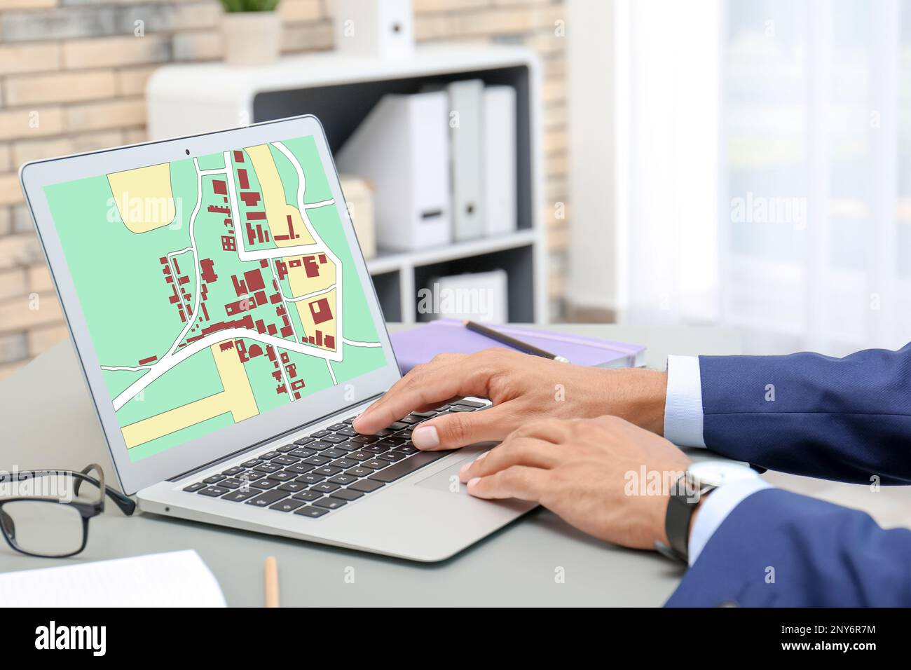 Man analyzing cadastral map on laptop at table, closeup Stock Photo