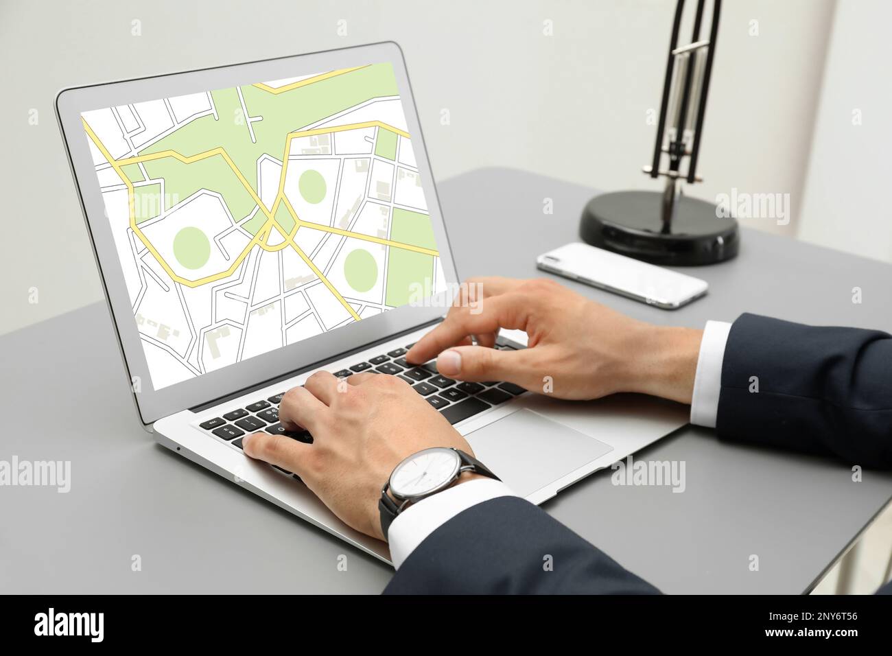 Man analyzing cadastral map on laptop at table, closeup Stock Photo