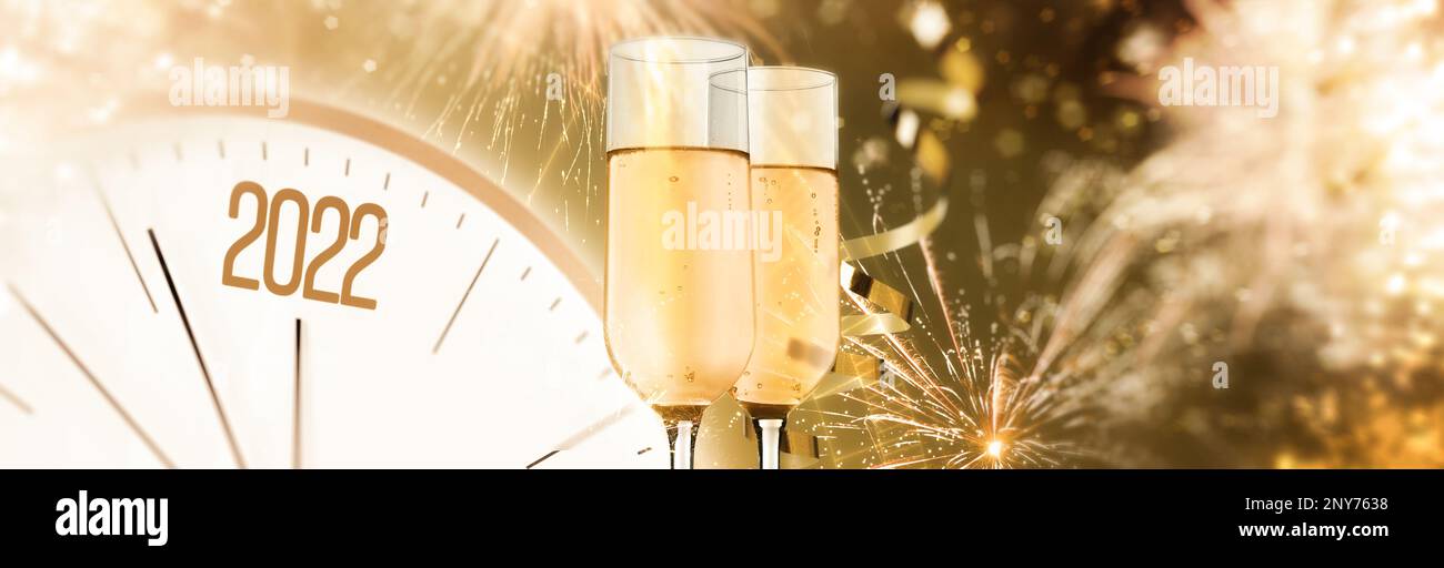 Glasses of sparkling wine, clock, shiny streamers and firework on color