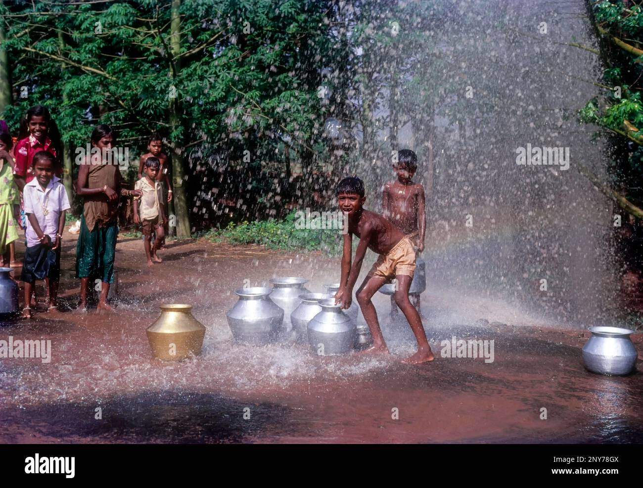 Silvery shower. Boys playing the water spray from the leakage of