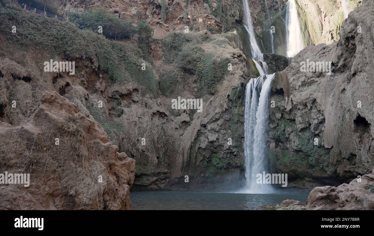 Sunny cliffs landscape with picturesque waterfall. Action. Water reservoir surrounded by cliffs Stock Photo