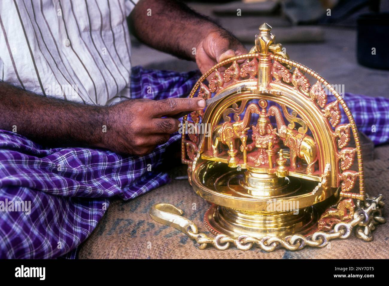 An artisan carving decorated bronze oil lamp making at Kunnamangalam