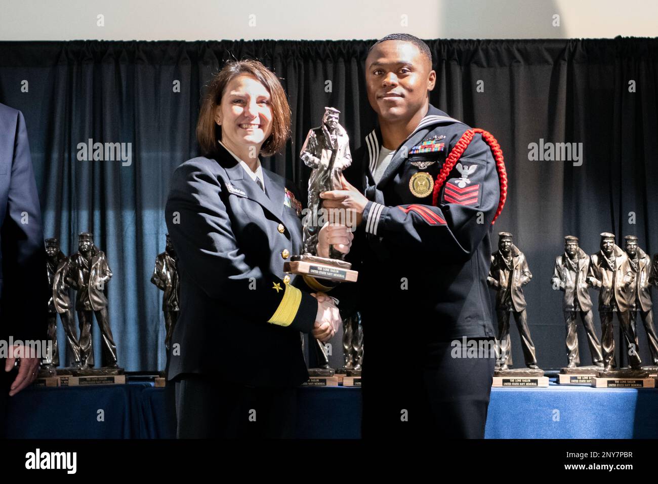 Rear Adm. Jennifer Couture, commander, Naval Service Training Command (NSTC), poses for a photo with Interior Communications Electrician 1st Class Daquan King, Recruit Training Command's Recruit Division Commander of the Year, during the Lake County Navy League's Sailor of the Year (SOY) awards ceremony at the National Museum of the American Sailor in Great Lakes, Il. Jan. 25. More than 40,000 recruits train annually at the Navy's only boot camp. Stock Photo