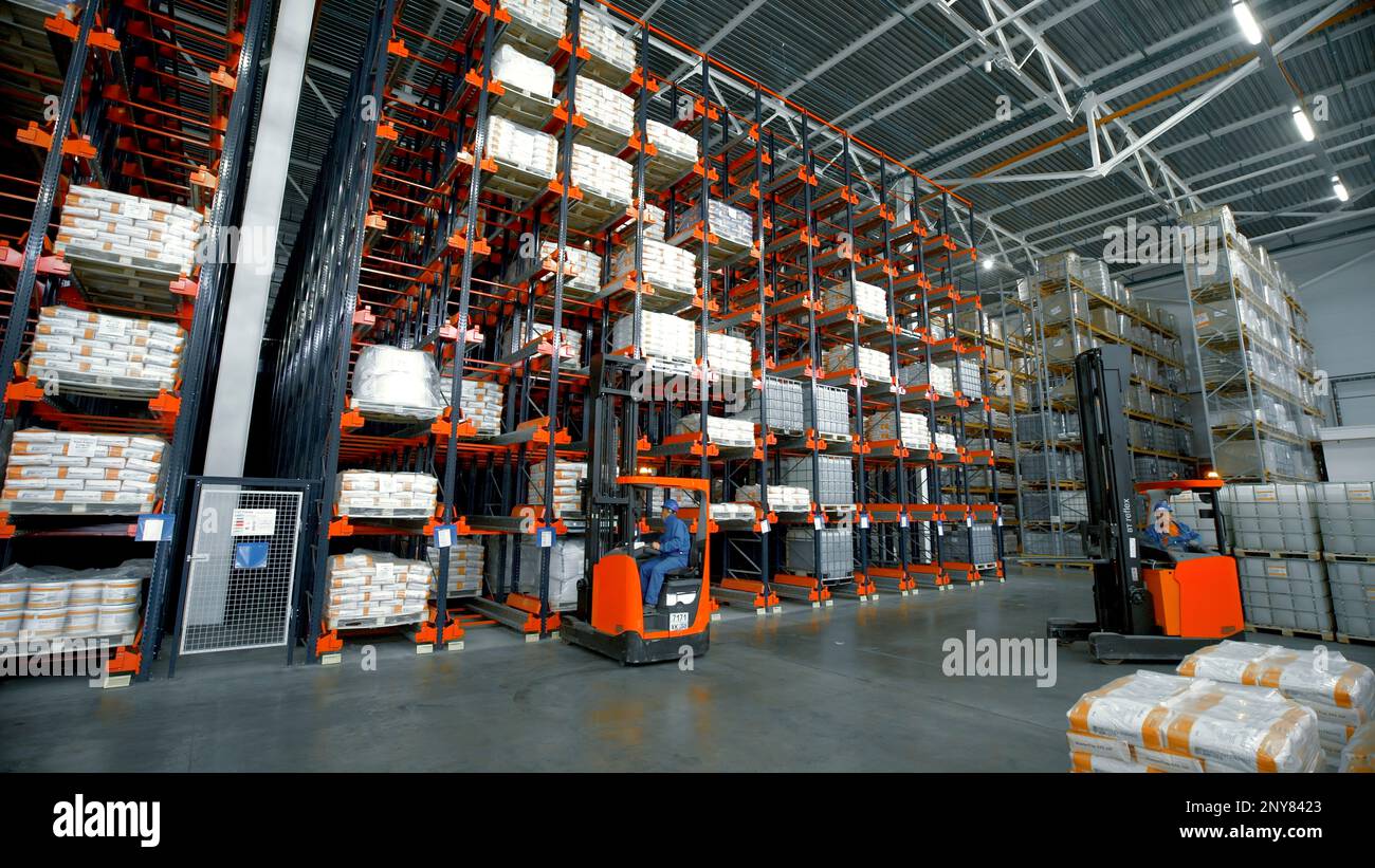 Serbia - Belgrade, September 20, 2022: Goods lay on shelves in large warehouse with loaders at factory. Creative. Sorting and distribution facility fo Stock Photo