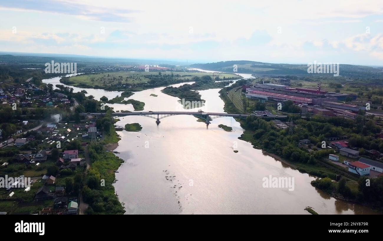 Aerial view of a summer city crossed by a wide river. Clip. Bridge connecting two sides of a town Stock Photo