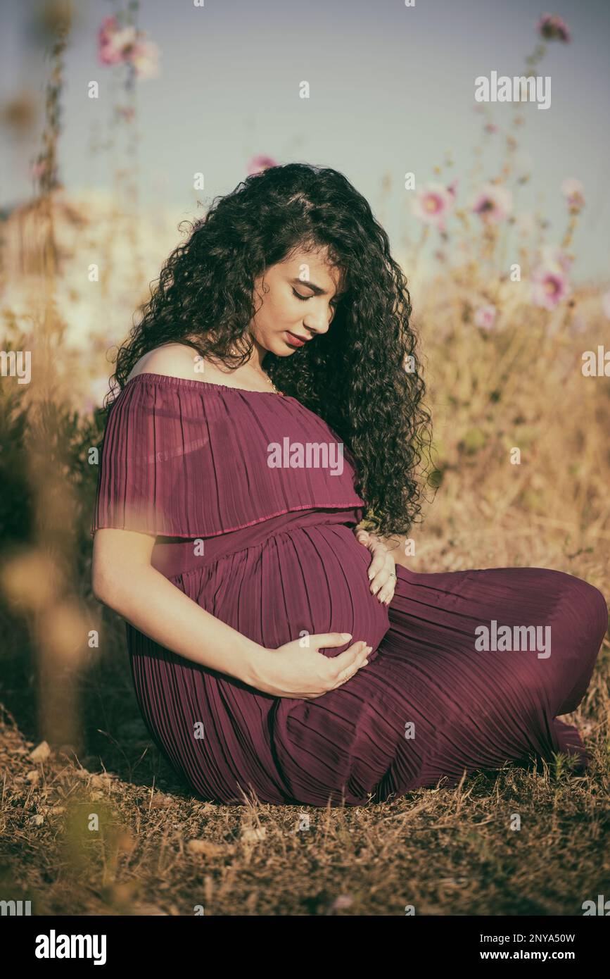Pregnant woman sitting outdoors Stock Photo