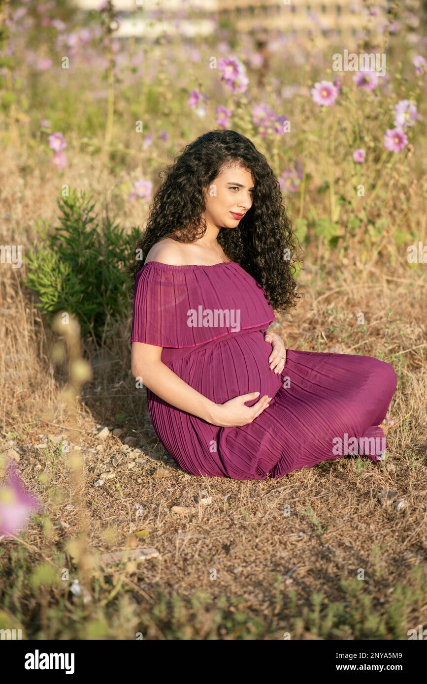 Pregnant woman sitting outdoors Stock Photo