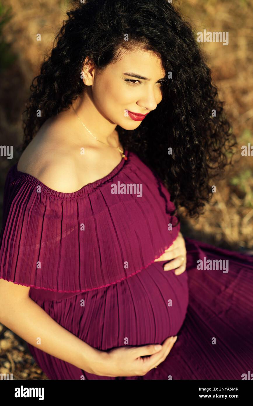 Pregnant woman sitting outdoors Stock Photo