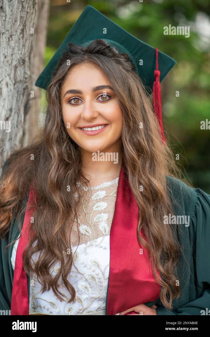 Beautiful young woman in cap and gown graduation Stock Photo