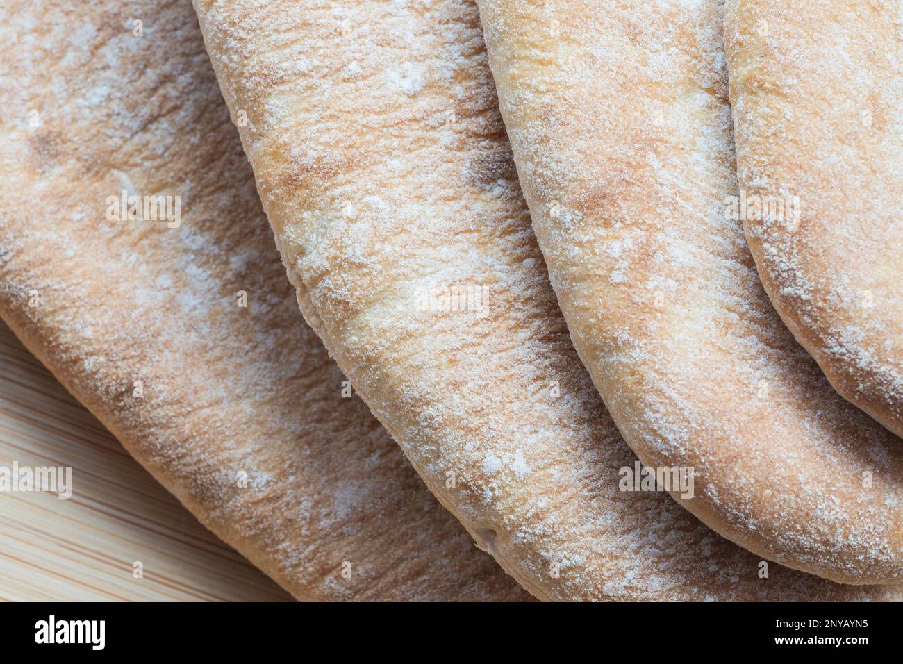 Layered configuration of greek pita bread on bamboo cutting board. Food